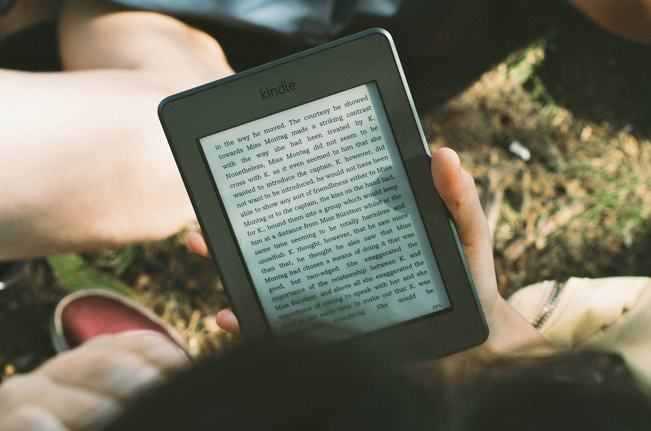 Person hält Amazon Kindle e-Reader in der Hand und liest