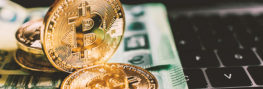 Bitcoin Münze und Euro Scheine liegen auf Laptop